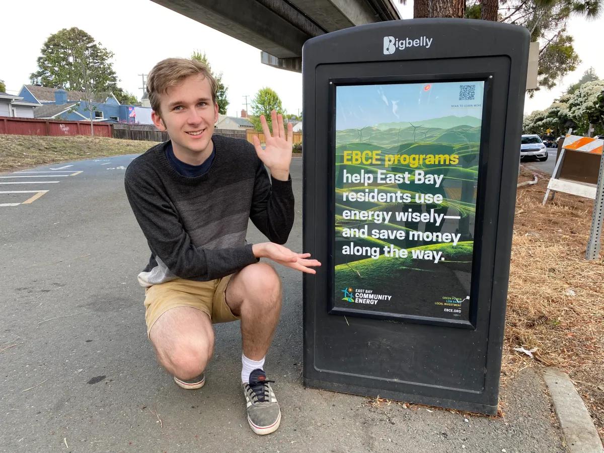 Jerome Paulos, A Berkeley High Alum Who Partnered With His Dad To Build An Clean Energy Incentive Finder For East Bay Residents, Poses Next To An Ebce Advertisement. Courtesy: Ben Paulos