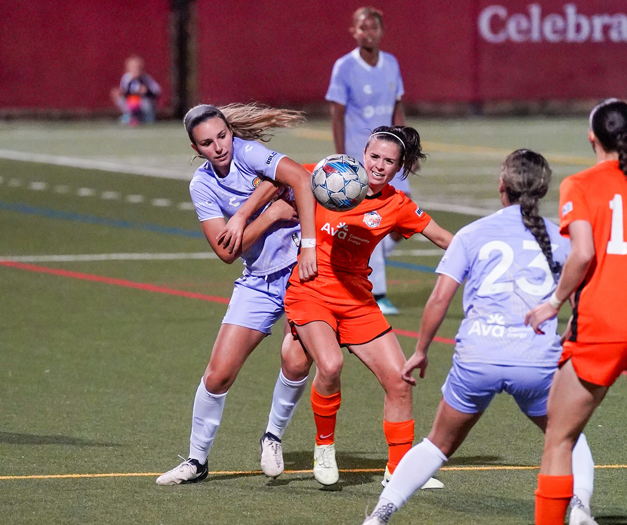 The Oakland Soul and Pleasanton Rage women's soccer teams battle for a ball. Both teams have Ava's logo on their jerseys.