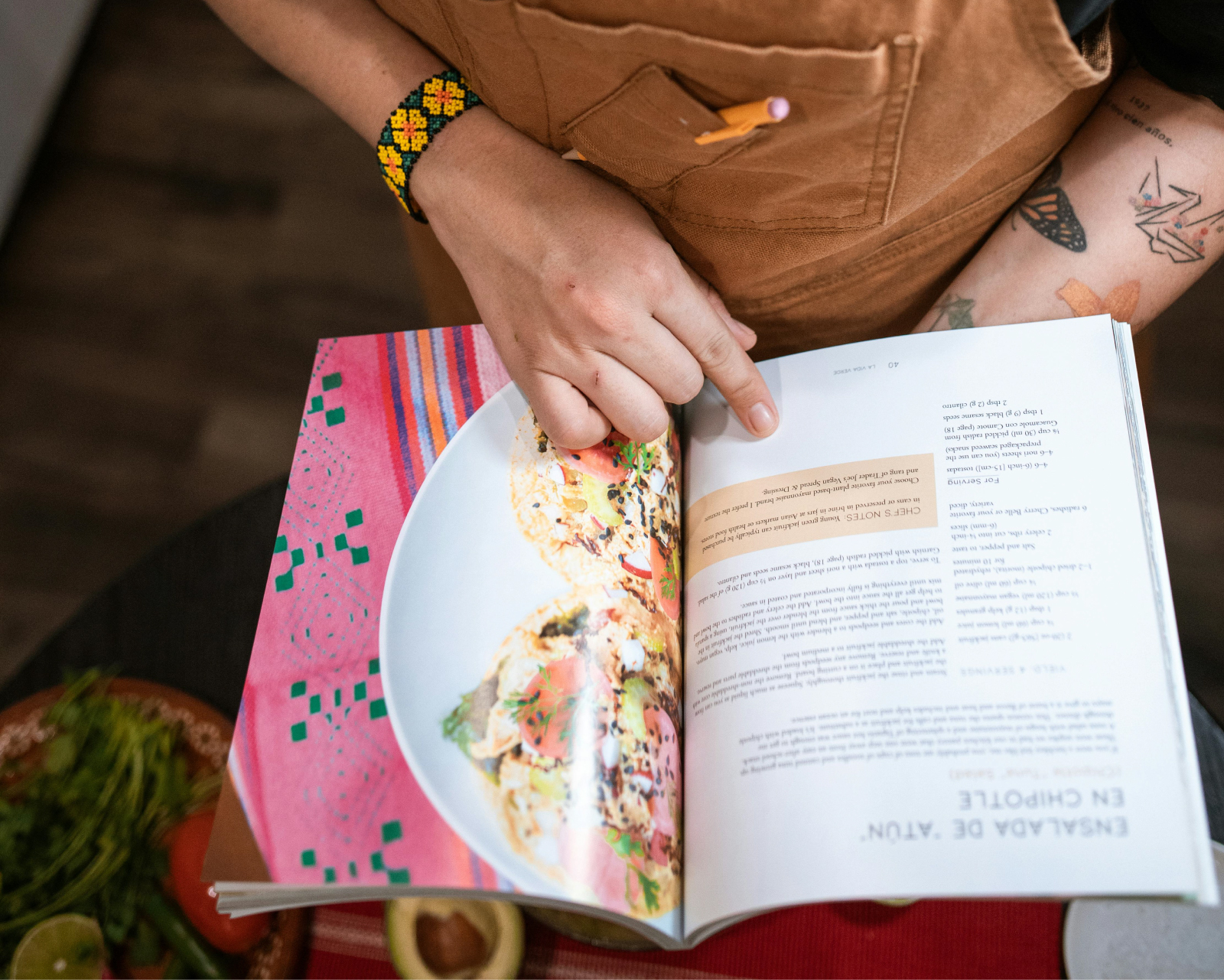 Person's hands holding a cookbook open to a page with a chipotle salad recipe