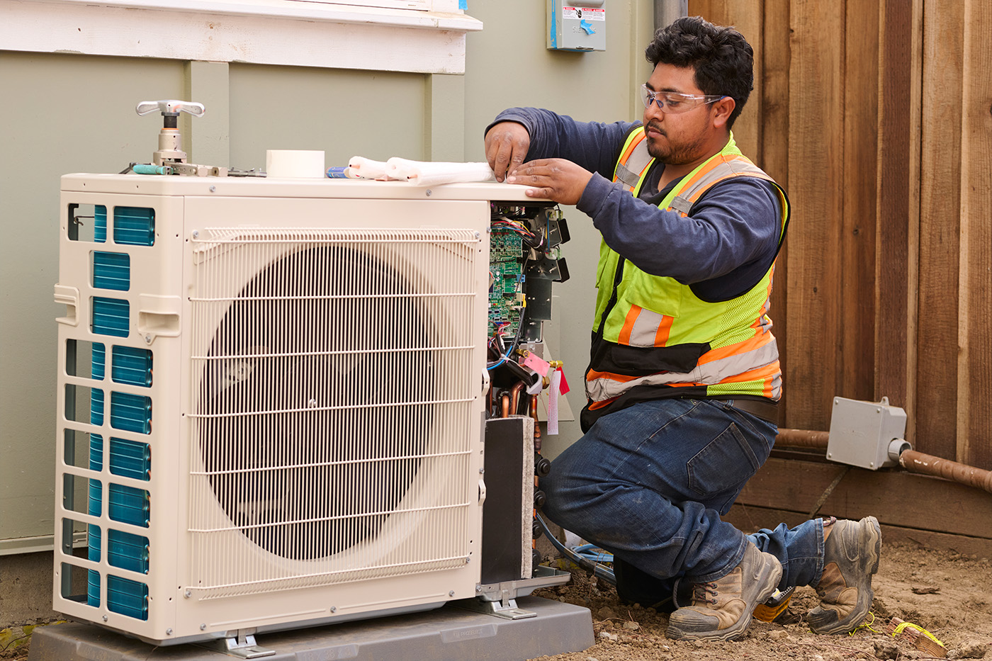 Worker Installing Exterior Piece Of A Heat Pump On A Home At Sequoia Grove