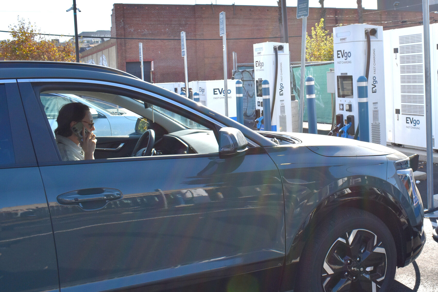 Person Talking On The Phone Inside An Electric Vehicle While The Vehicle Charges